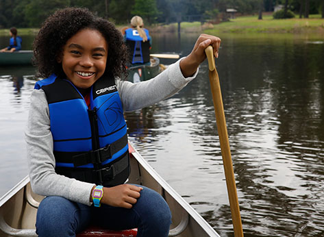 Young girl laughing while canoeing on a river
