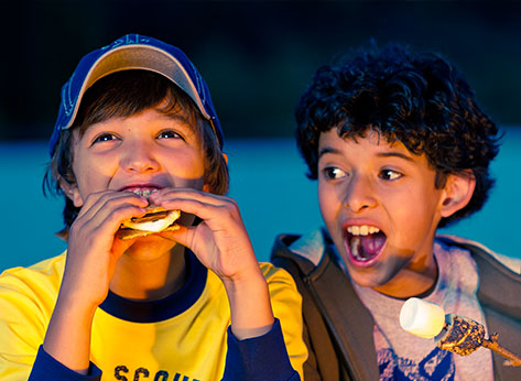 An excited pair of Scouts eating and cooking s'mores