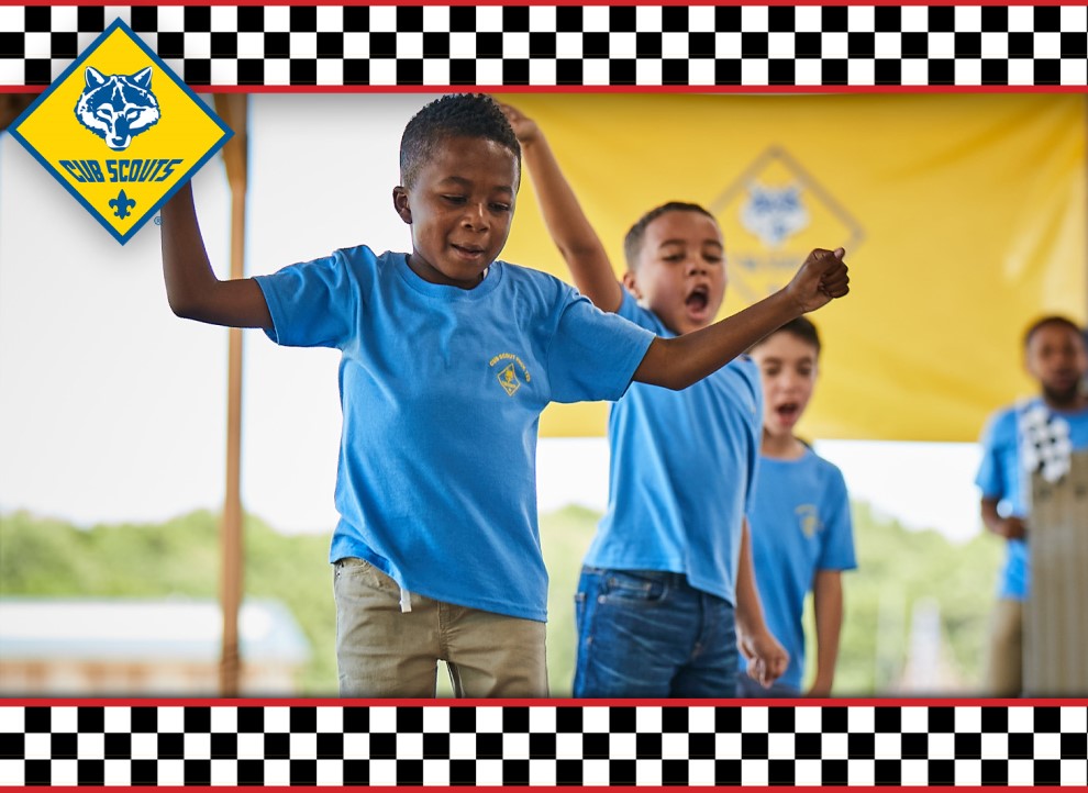 Scout smiling and cheering as the pinewood derby race continues