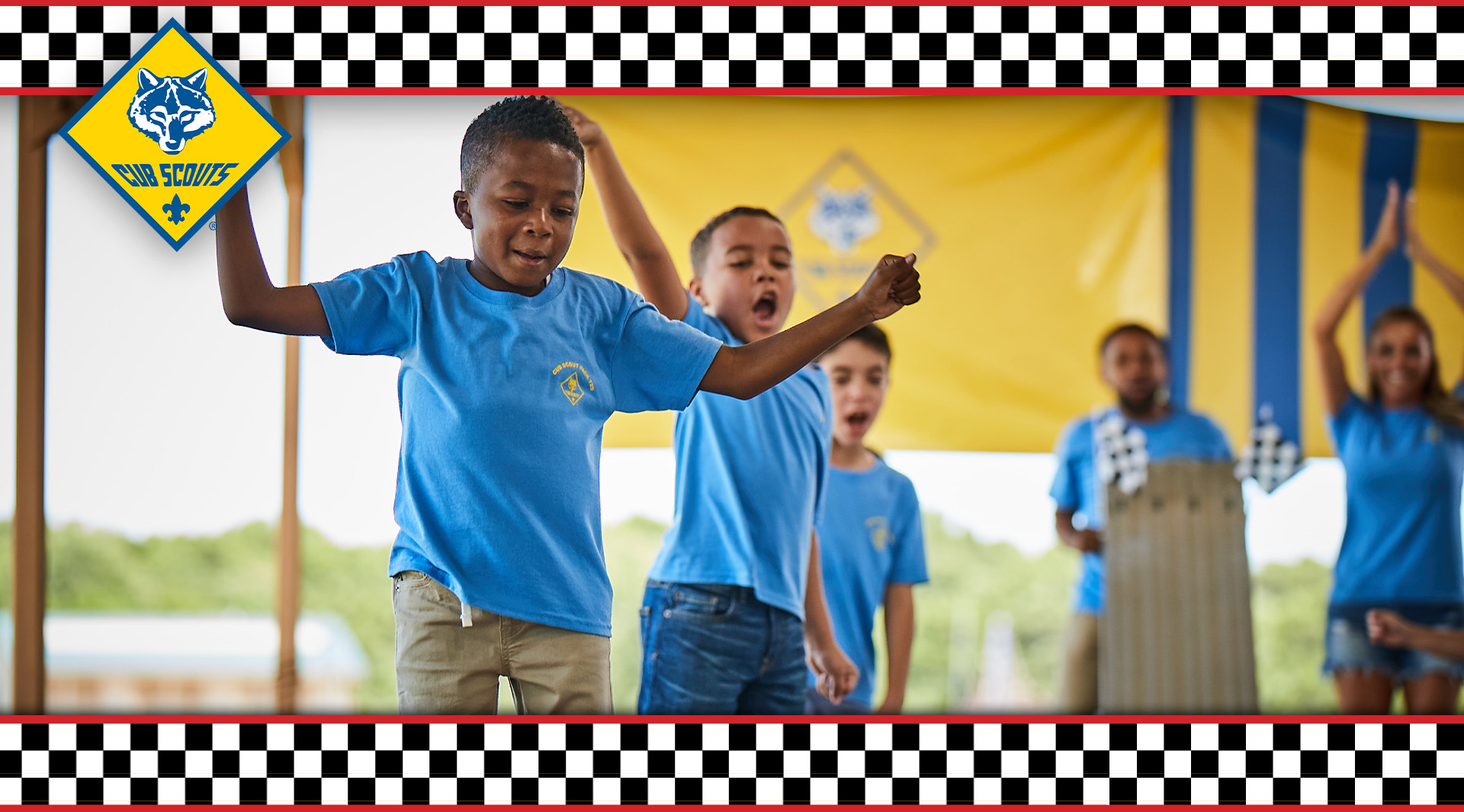 Scout smiling and cheering as the pinewood derby race continues