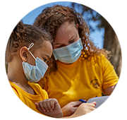 Mother and daughter with masks looking at something off-screen