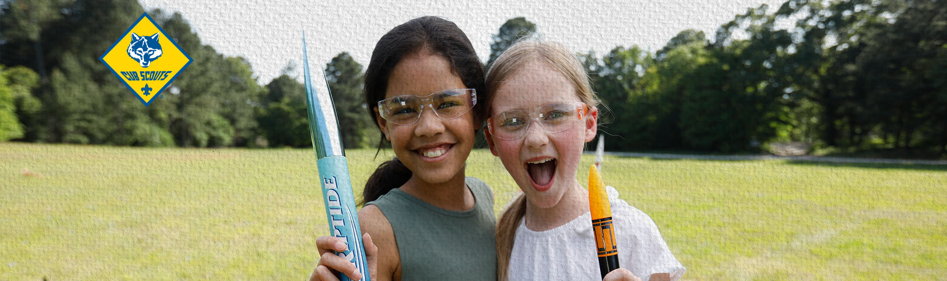 Two female Scouts excitedly cheering while holding model rockets
