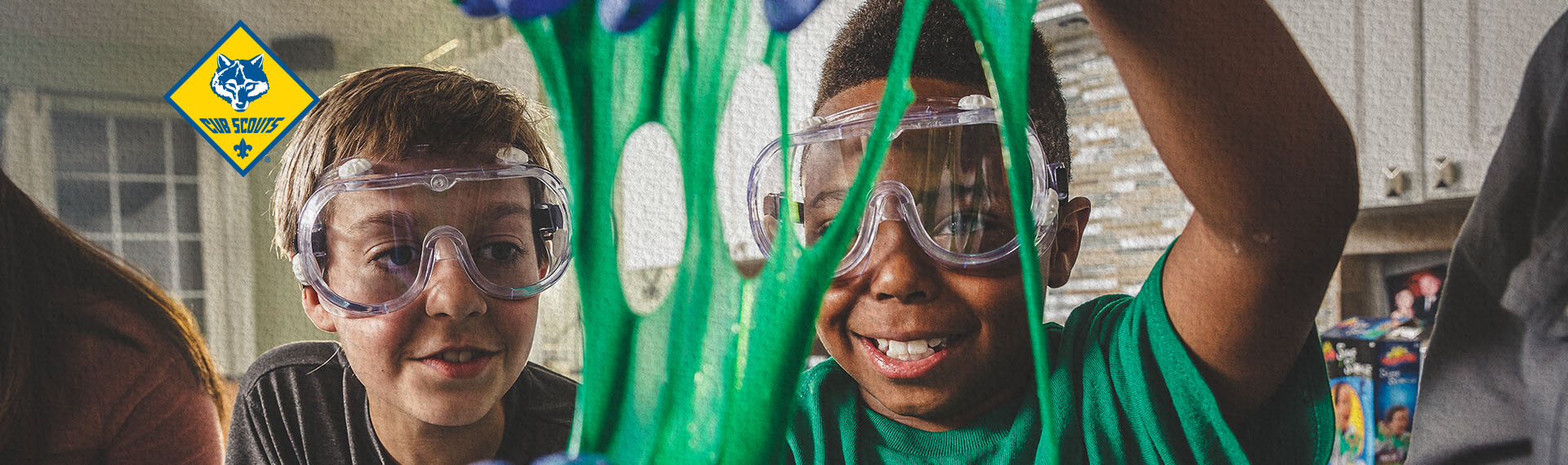 Two male Scouts smiling while doing an experiment with green goo