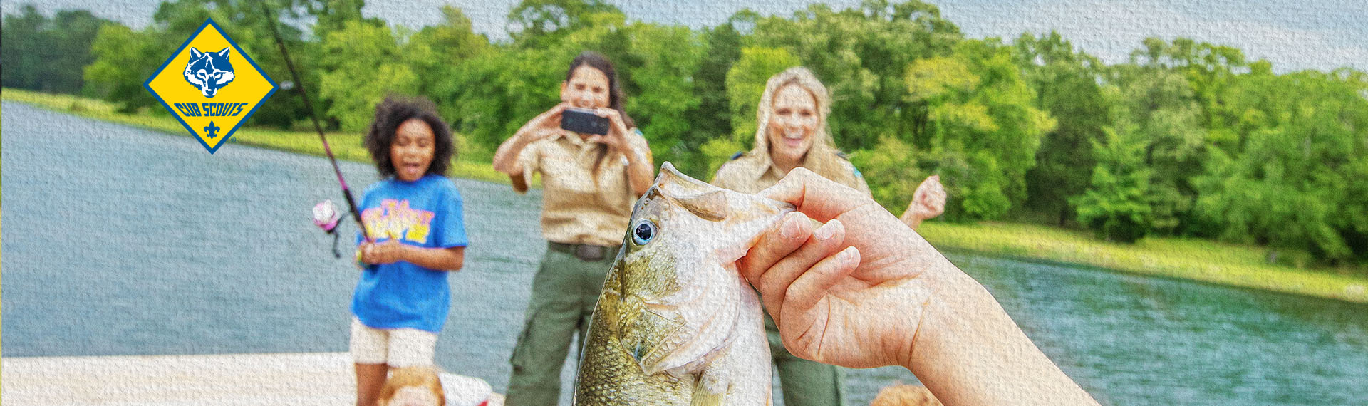 2 adult leaders in uniform cheering as the Scout behind the camera shows the fish they caught